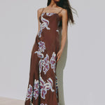 Brown floral maxi slip dress with thin straps, featuring a blue and cream abstract floral print and a straight neckline.