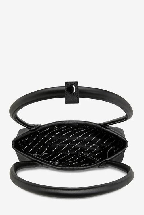 A black leather handbag with a unique open-top design, featuring a thick circular handle, a diamond-quilted interior with white stitching, and a small square metal accent on the handle, shown against a plain light gray background.