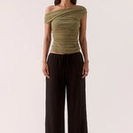 Woman wears a green ruched top and black pants