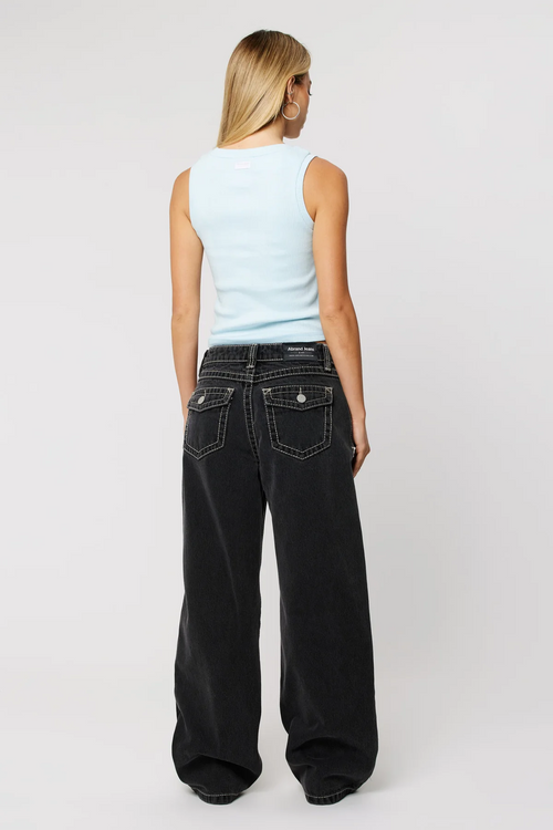 Woman wearing baggy black jean and blue baby tee with sneakers