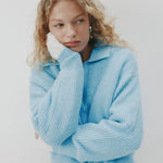 Woman wearing a light blue sweater against a white background