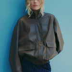 Person wearing a brown jacket and blue pants against a blue wall