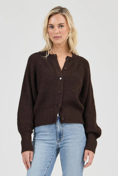 Woman wearing a brown cardigan and light blue jeans on a white background