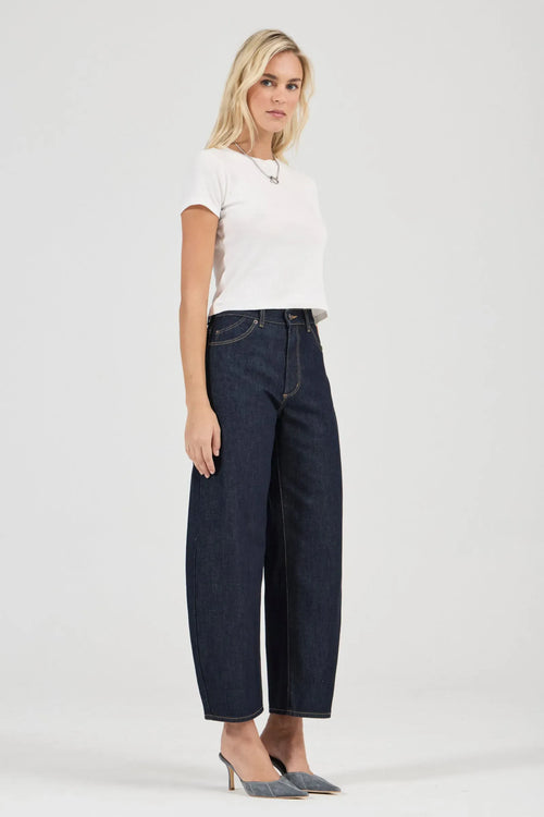 Woman wearing dark blue jeans and a white top on a white background