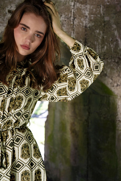 Woman wearing a patterned dress with a textured wall background