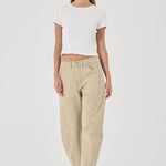 A model wearing a white ribbed short-sleeve crop top and beige wide-leg baggy pants, standing against a light gray studio background.