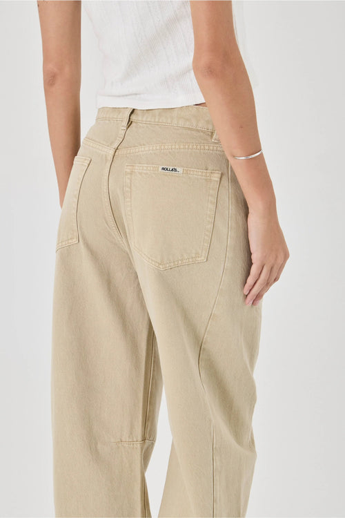 A person shown from the back wearing light beige wide-leg jeans with a white ribbed top, photographed against a clean light gray studio background.