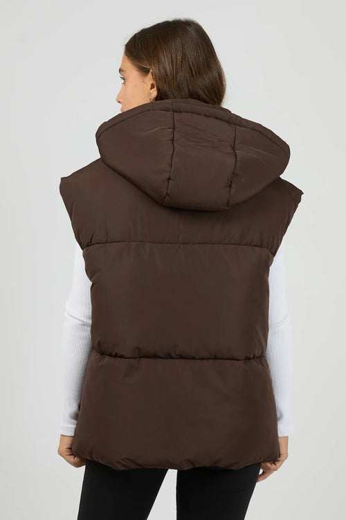 Woman wearing a brown puffer vest on a white background