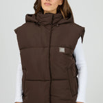 Woman wearing a brown puffer vest on a white background