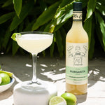 Margarita bottle with a glass of margarita and limes on a natural background
