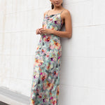 Model wears a blue floral maxi dress with a tie back and adjustable straps