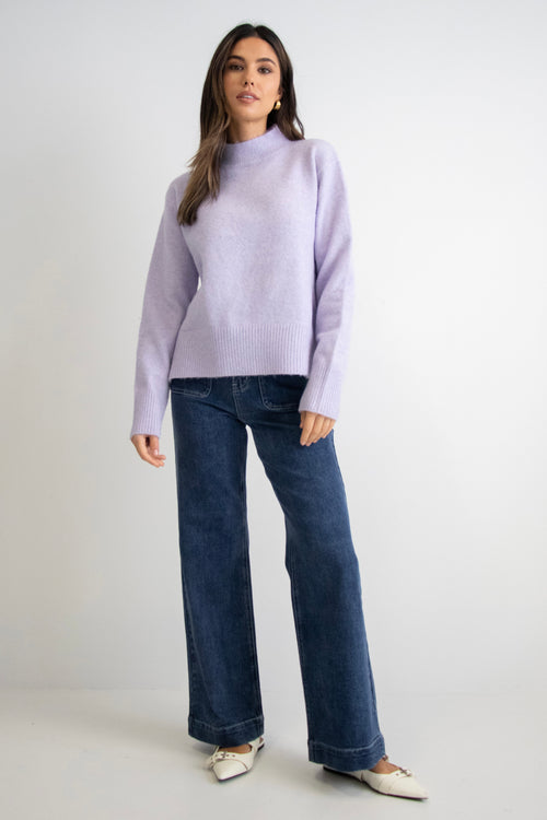 model wears a purple knit with dark blue jeans