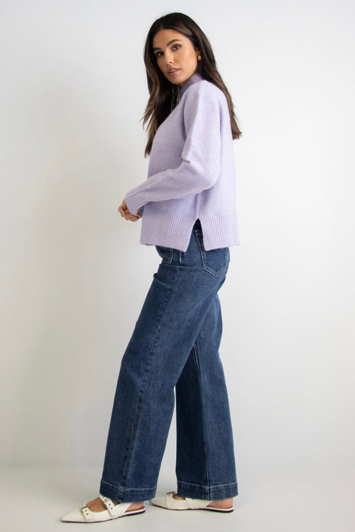 model wears a purple knit with dark blue jeans
