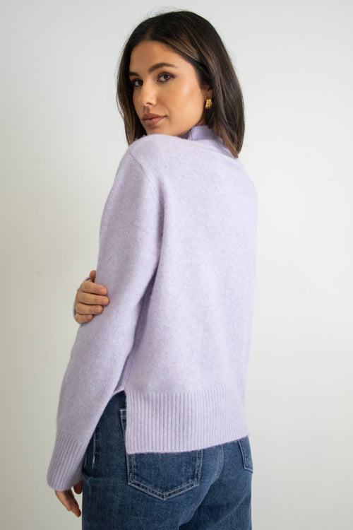 model wears a purple knit with dark blue jeans