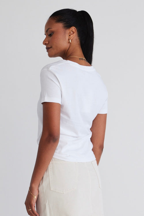 model wears a white tee with ecru skirt