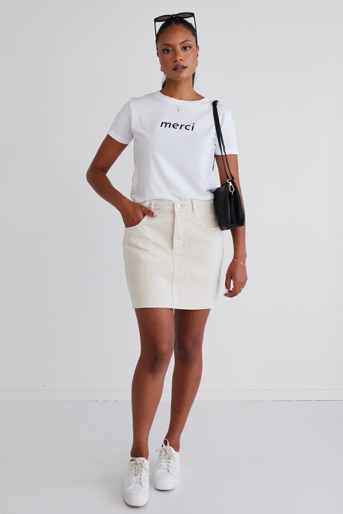 model wears a white tee with ecru skirt