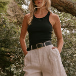 model wearing beige linen shorts and a black cotton singlet