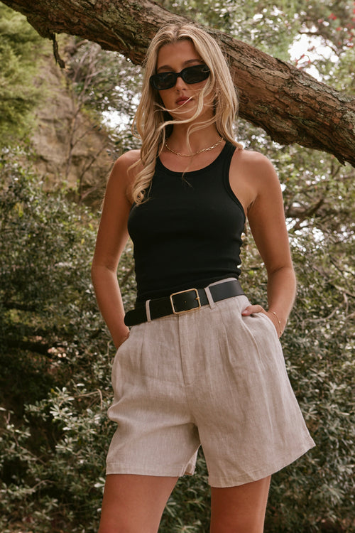 model wearing beige linen shorts and a black cotton singlet