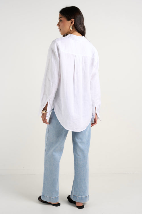model wears a white linen shirt with blue jeans