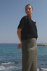 Woman wearing a khaki linen midi skirt and black crochet knit top by the beach