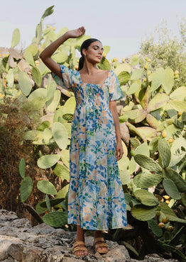 model is outside and wears and blue and orange floral maxi dress with sandals