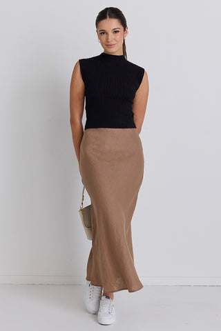 Model wears a brown linen maxi skirt with black top 