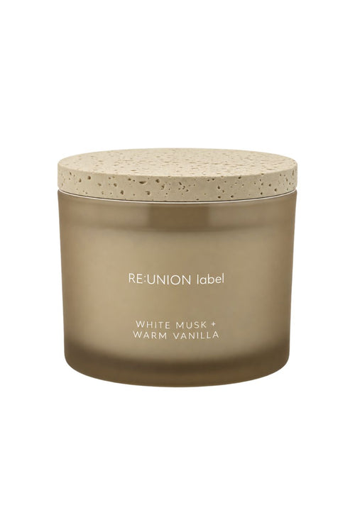 A frosted glass jar candle with a speckled beige lid, labeled 'RE:UNION label' and 'WHITE MUSK + WARM VANILLA' on a plain white background.
