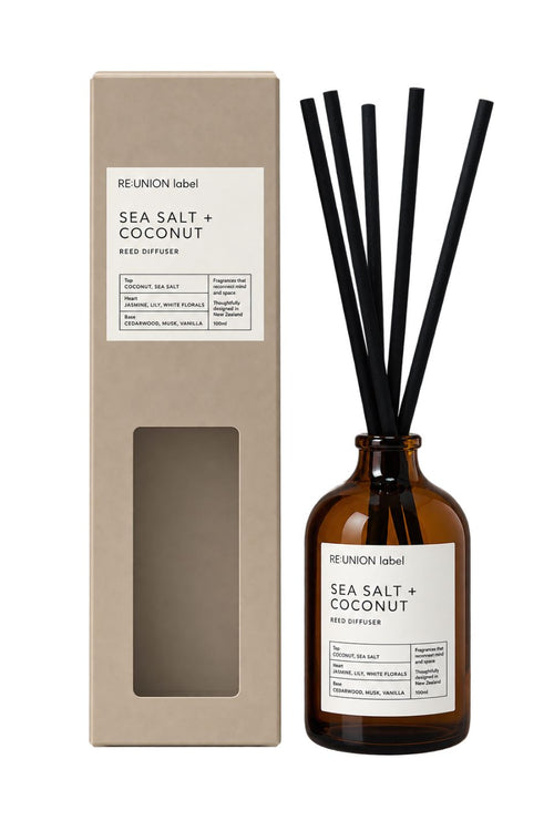 Re:union Label Sea Salt + Coconut Reed Diffuser shown with its tall beige cardboard box and an amber glass bottle containing black reed straws, on a white background.