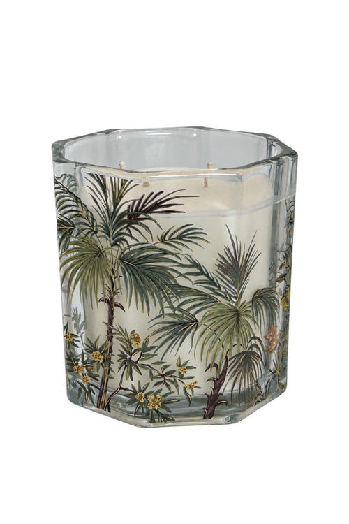 A hexagonal glass jar candle with a white wax fill and a printed tropical palm tree and floral design on the front, shown against a plain white background.