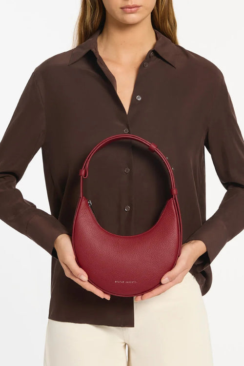 Person holding a red handbag against a plain background