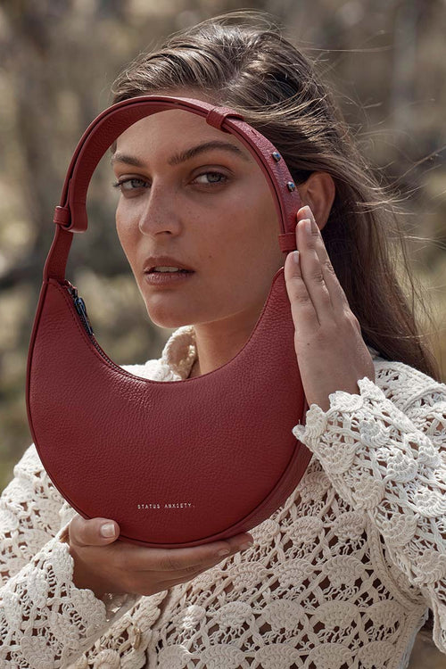 Woman holding a red handbag with a blurred natural background