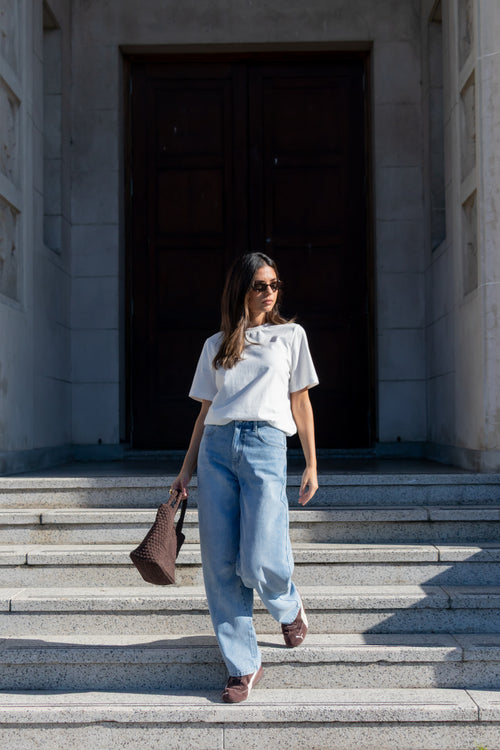 Woman walking up steps in front of a large building entrance