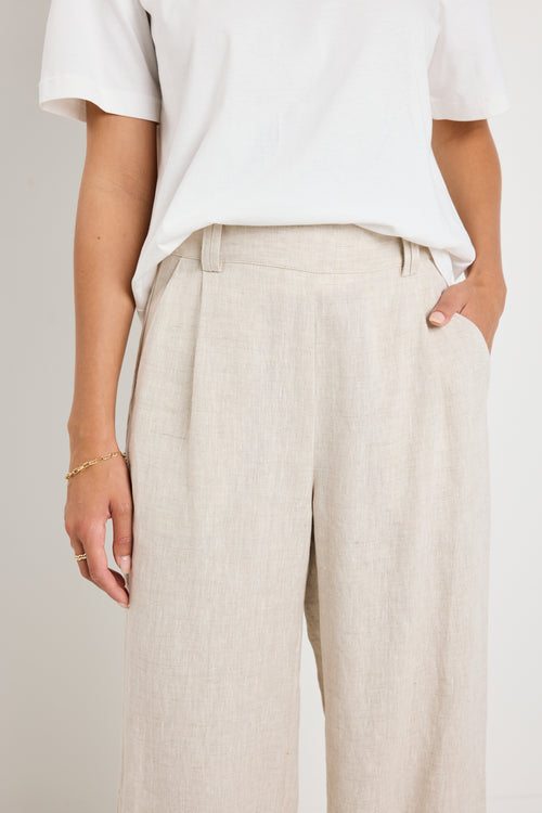 model wears natural linen pants with white top