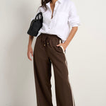 Model wears brown track pants