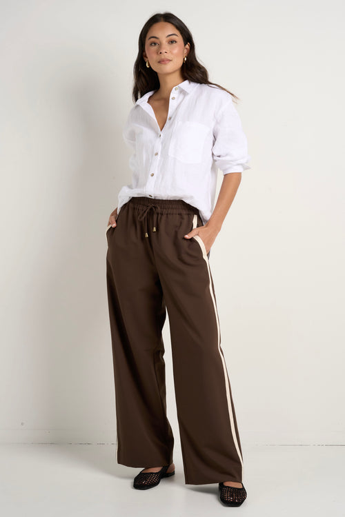 Model wears brown track pants