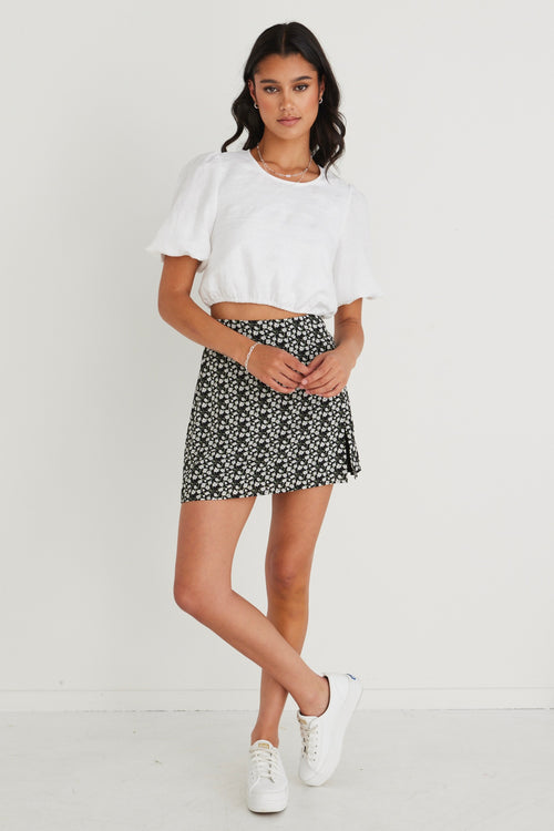 model wearing white top and black floral mini skirt