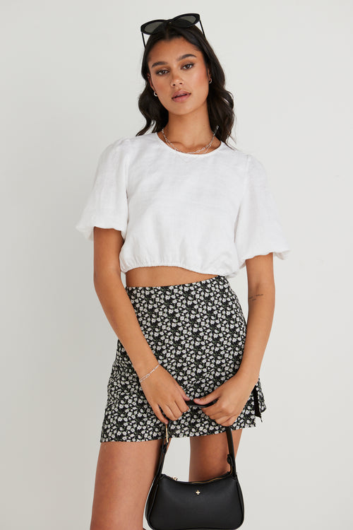 model wearing white top and black floral mini skirt