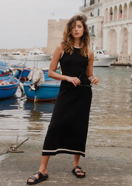 model wears black rib knit maxi dress outside by the water