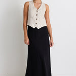 model wears linen vest and black linen maxi skirt with white sneakers