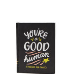 Black notebook with 'You're a good human' text on a white background