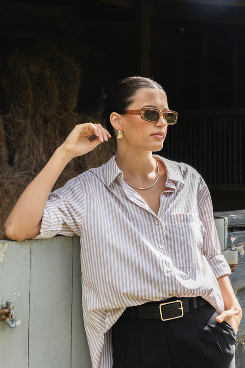 model wears a ecru stripe shirt with black pants