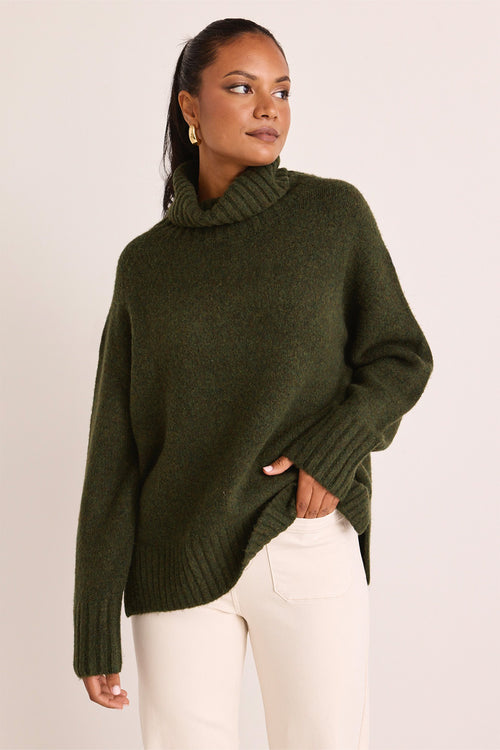 model wears a green turtle neck knit