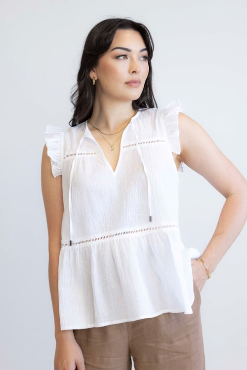 model wears white sleeveless top with brown pants